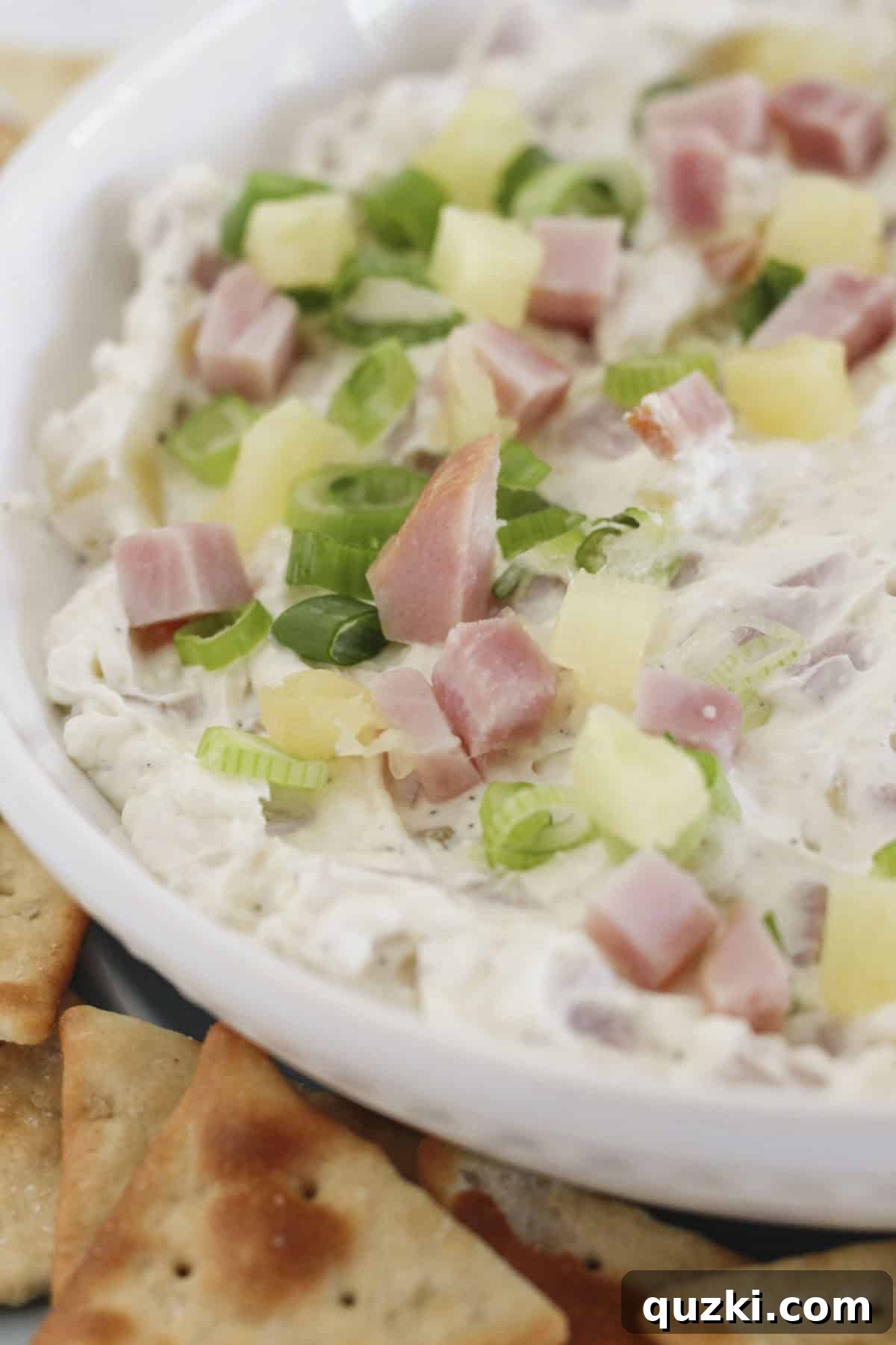 Effortless Hawaiian Ham Dip 2 Hawaiian dip in a white bowl and ready to serve, garnished with green onions.