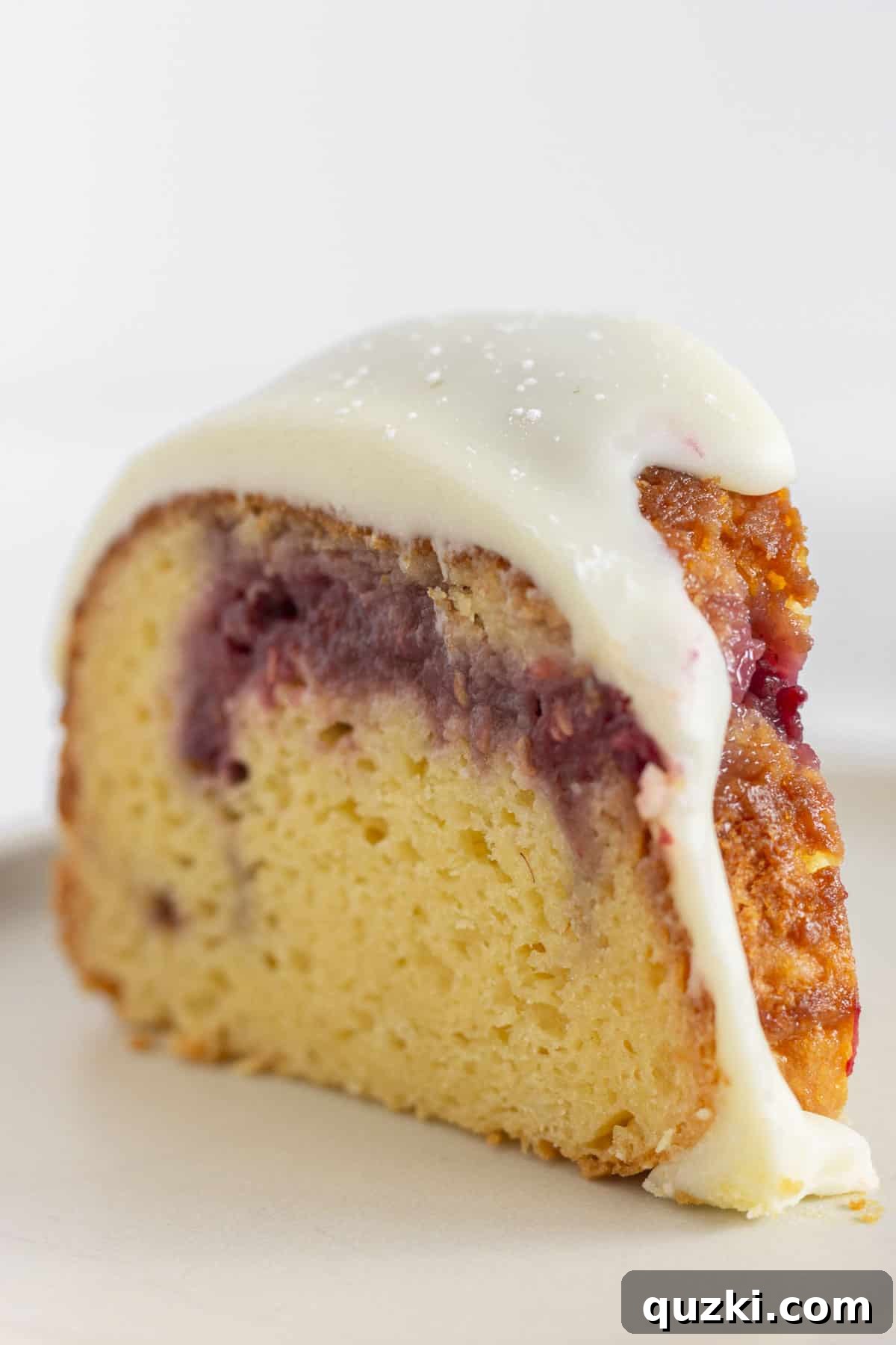 A slice of raspberry cake with white chocolate ganache.