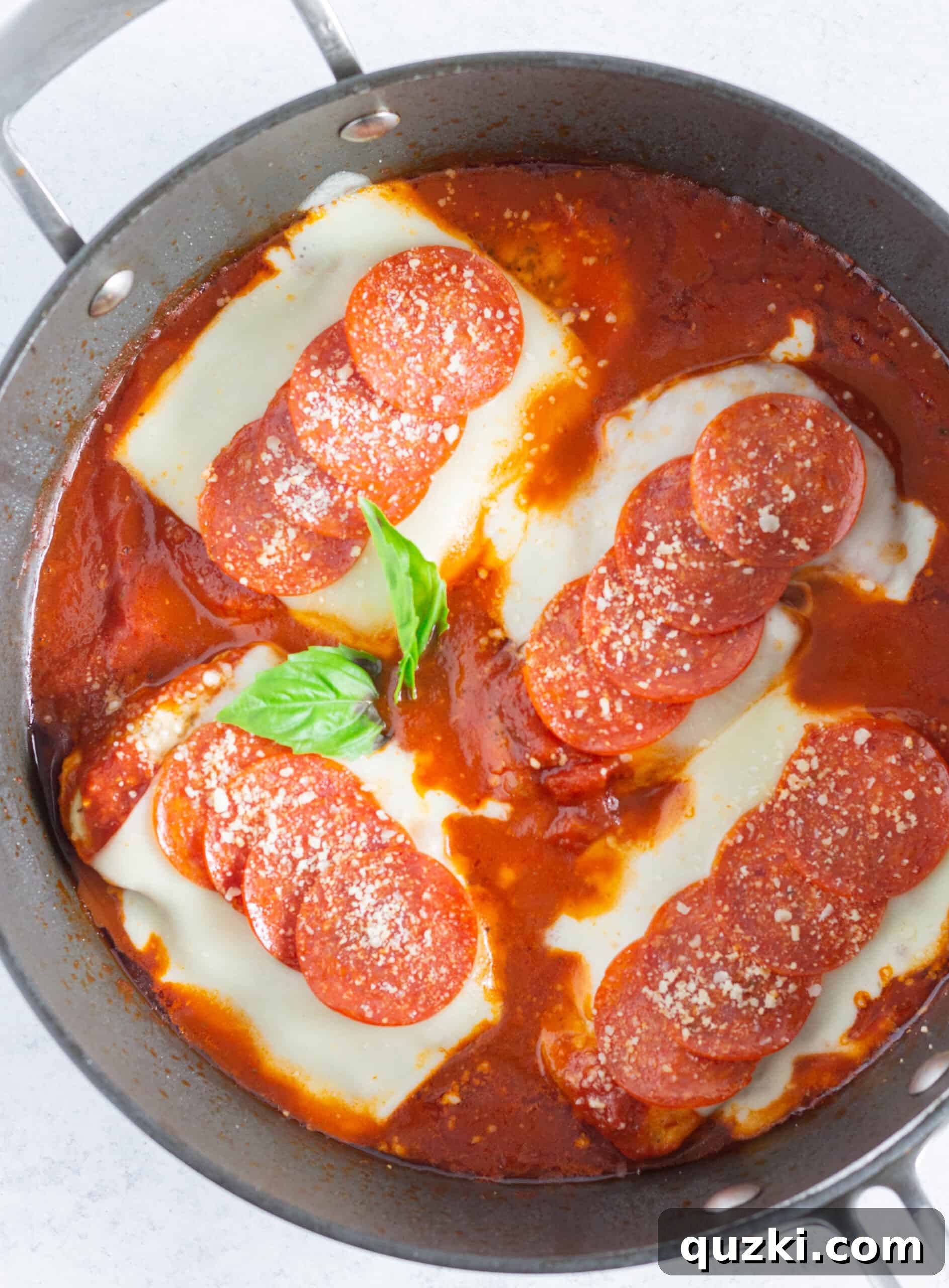Looking down at a skillet of pepperoni pizza chicken.