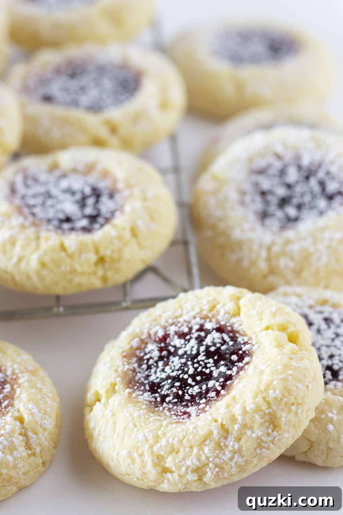 Golden Yellow Cake Mix Thumbprint Gems 2 Delicious Yellow Thumbprint Cookies with vibrant jam centers, elegantly arranged on a cooling rack and dusted with powdered sugar, ready for enjoyment.