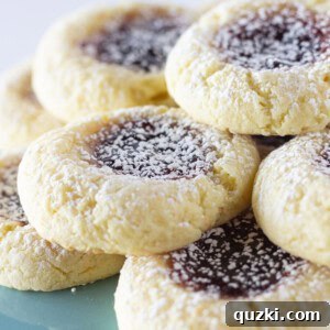 A delightful close-up of yellow thumbprint cookies on a teal cake plate, highlighting their perfect golden hue and jam centers.
