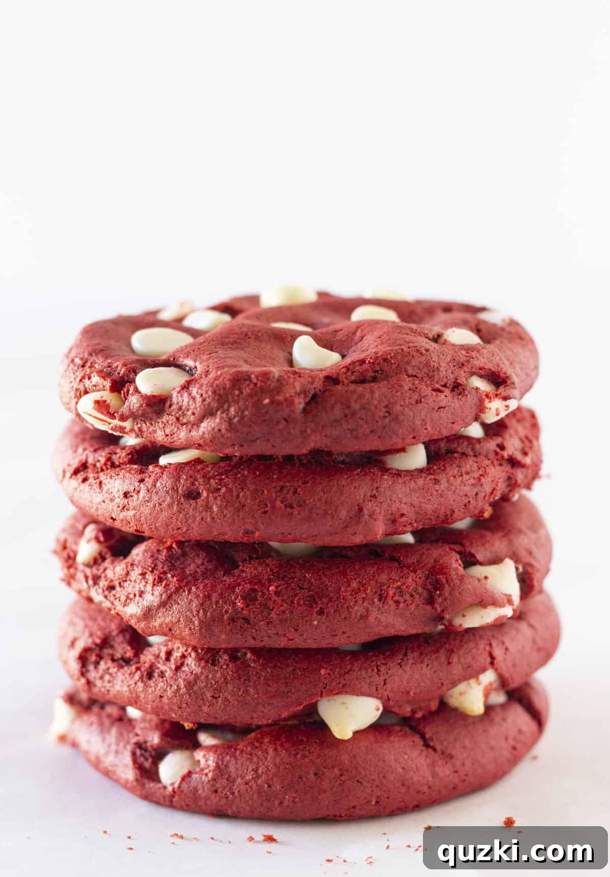 Stacked red velvet cookies with white chocolate chips, showcasing their vibrant color and soft texture.
