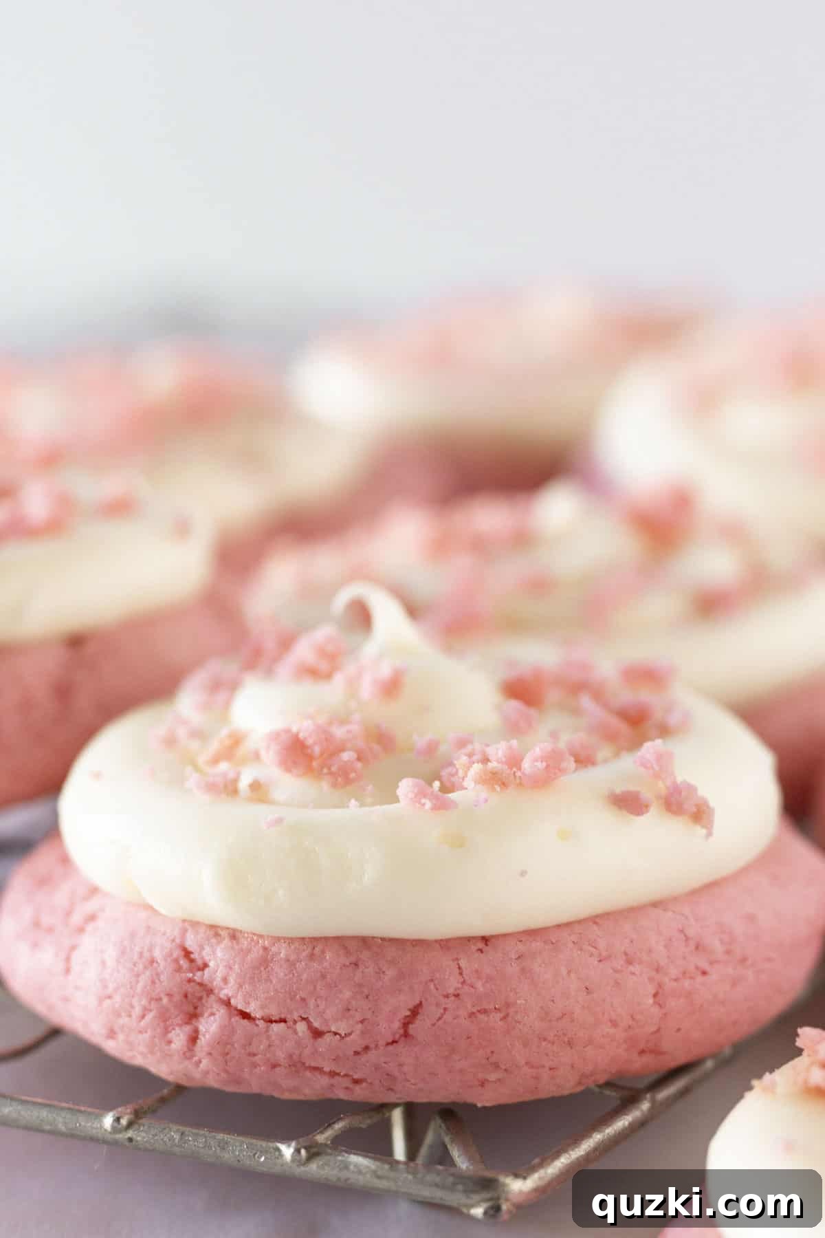 Frosted Pink Velvet Cookies on a cooling rack.