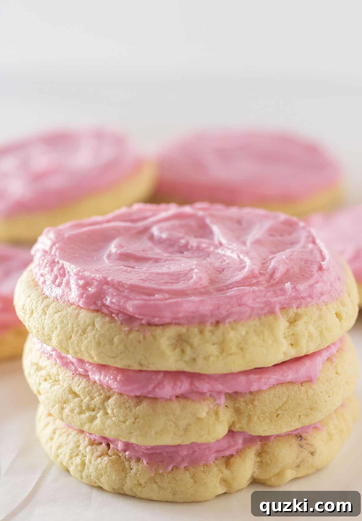 Stacked Crumbl copycat chilled sugar cookies with pink frosting.