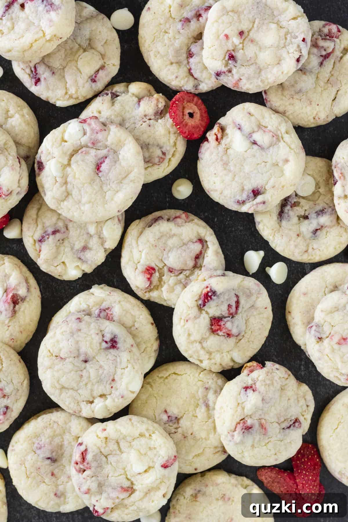 A large black tray filled with dozens of freshly baked strawberry cream cheese cookies, perfectly golden and pink.