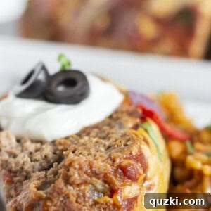 A slice of taco meatloaf with sour cream and olives on top.
