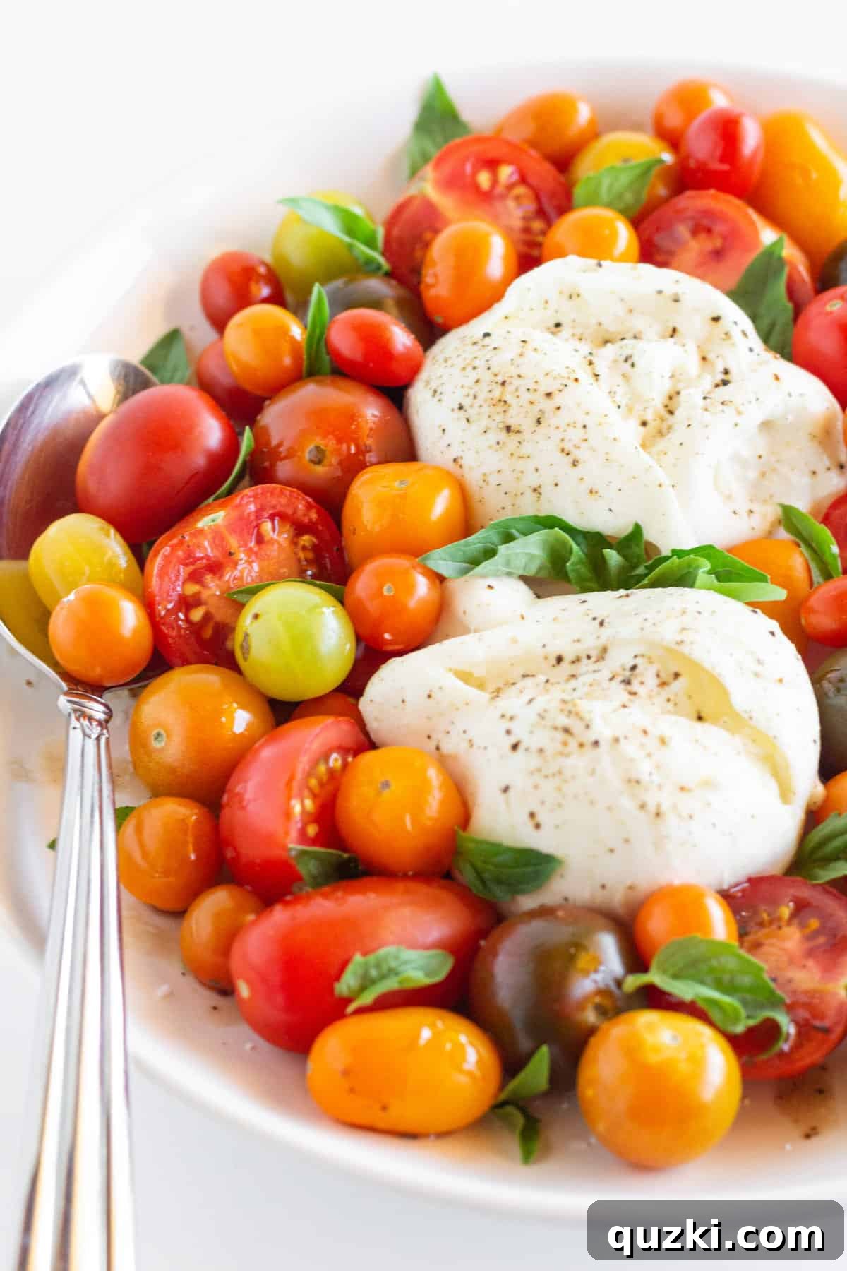 Luscious Burrata Caprese 6 A large platter of Burrata Caprese salad with various types of tomatoes, fresh basil, and two whole burrata balls, garnished with balsamic glaze.