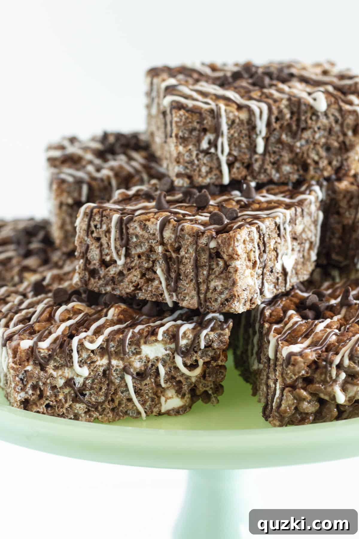 No-Bake Chocolate Crispy Squares 2 Chocolate Krispie Treats served on a green cake plate.