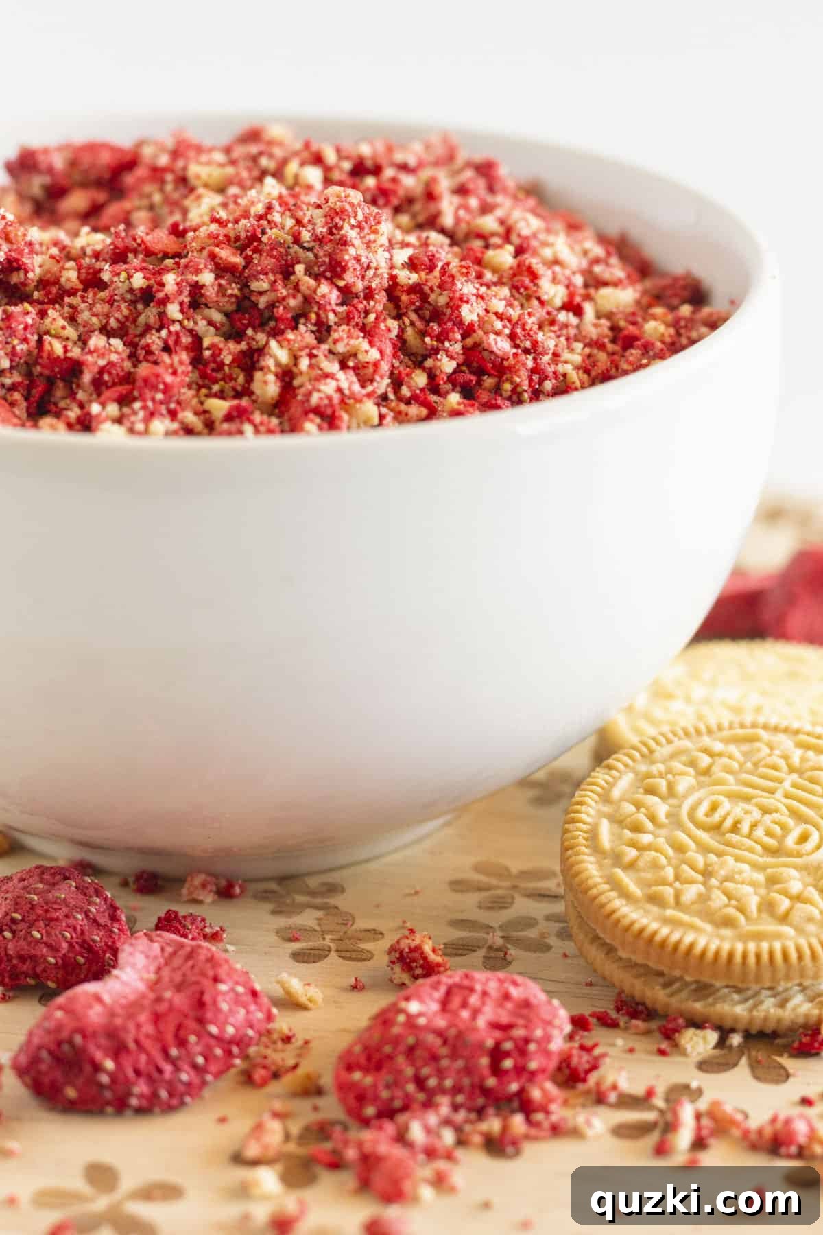 Irresistible Strawberry Crunch Topping 2 A close-up of a white bowl filled with golden-pink strawberry crunch topping, showcasing its textured, crumbly nature.