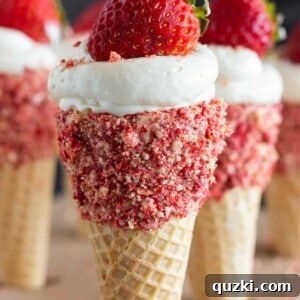 A beautifully presented Strawberry Crunch No Bake Cheesecake Cone with a fresh strawberry garnish.