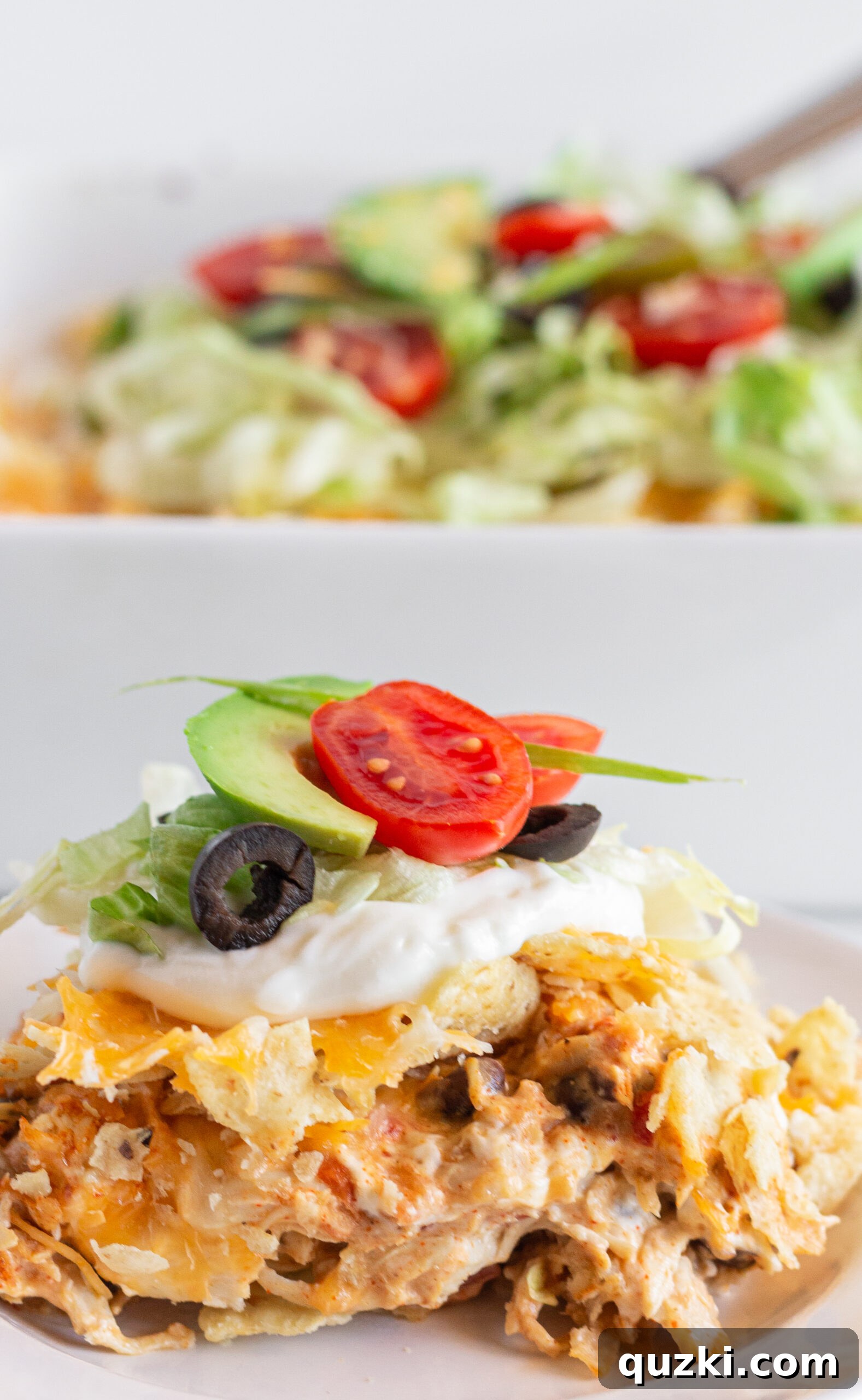 A vibrant serving of Easy Chicken Taco Casserole topped with fresh lettuce, diced tomatoes, and avocado.