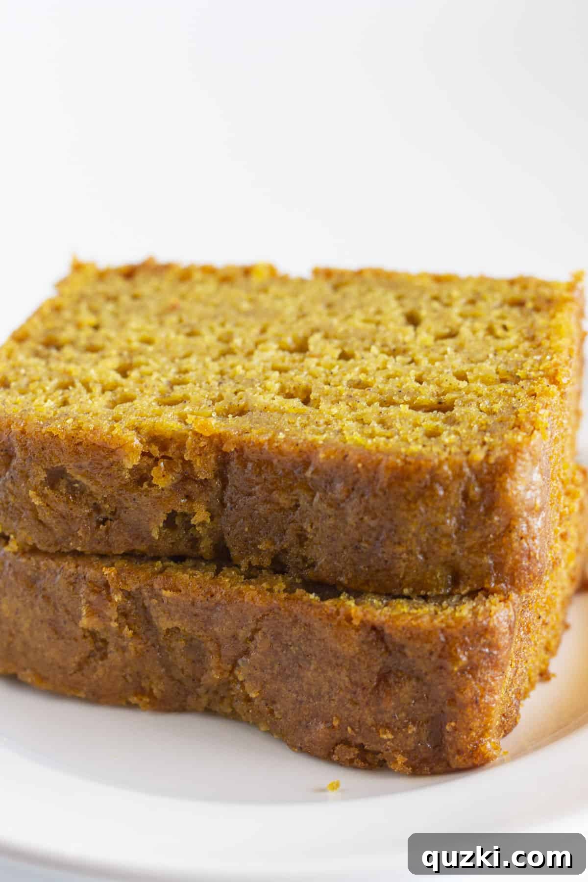 Cake Mix Shortcut Pumpkin Spice Loaf 6 Two enticing slices of pumpkin bread arranged neatly on a pristine white plate.