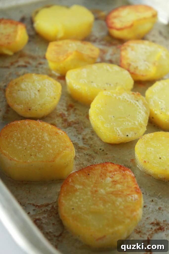Melt-in-Your-Mouth Roasted Potatoes 6 Partially roasted potato slices being carefully turned over in the baking dish for even crisping.