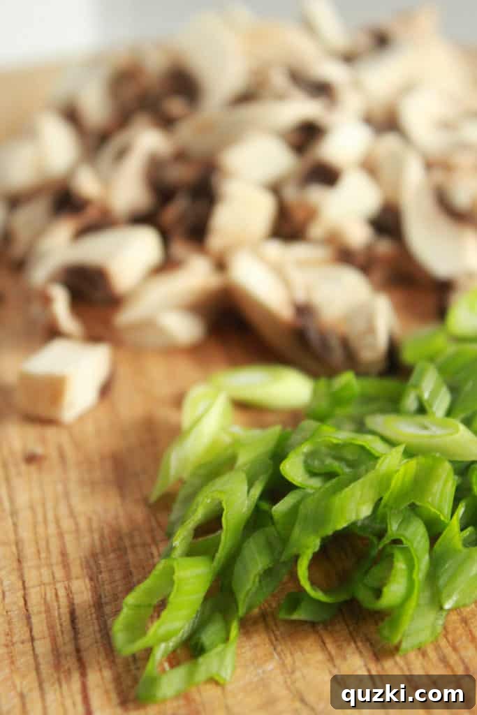 Vibrant Asian Turkey Lettuce Bites 3 Close-up shot of chopped button mushrooms and thinly sliced green onions on a cutting board, ready to be added to the ground turkey mixture for Asian Lettuce Wraps. Highlights fresh ingredients.