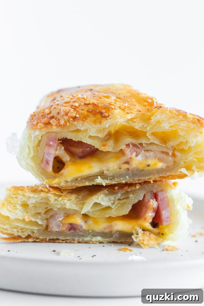 A Bacon Turnover cut in half showing the inside of each half with melted cheese and bacon pieces, showcasing the delicious filling and flaky pastry.