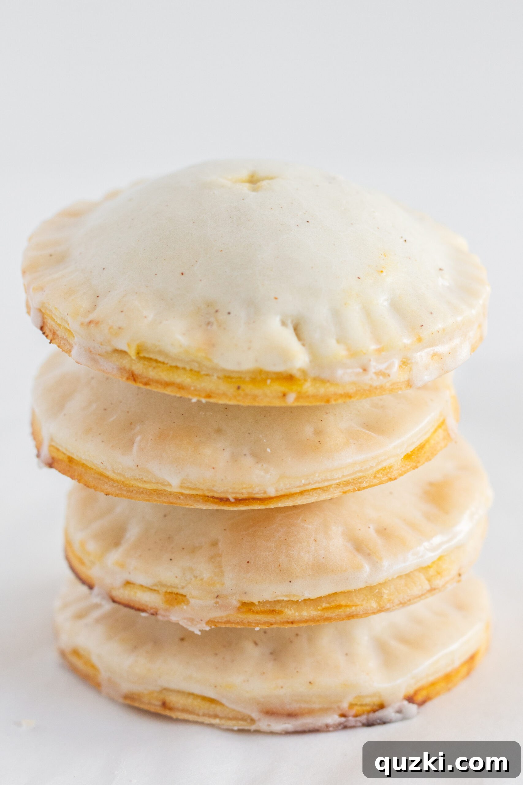 Four pumpkin hand pies beautifully stacked on top of each other, showcasing their rustic charm and delicious glaze.