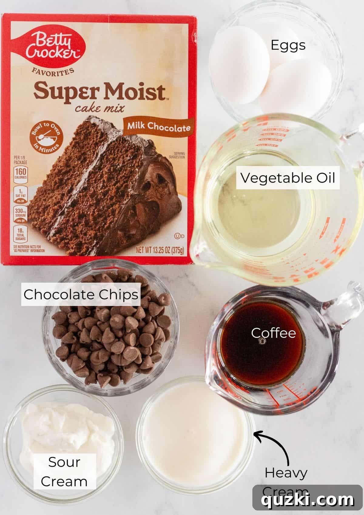 A flat lay photograph displaying all the essential ingredients laid out for making mini chocolate bundt cakes, including a cake mix box, eggs, oil, coffee, sour cream, chocolate chips, and heavy cream.