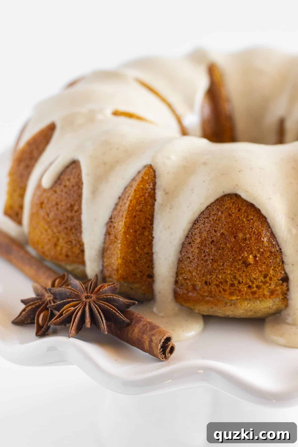 A beautifully frosted spice bundt cake, elegantly presented on a pristine white plate, ready to be served.