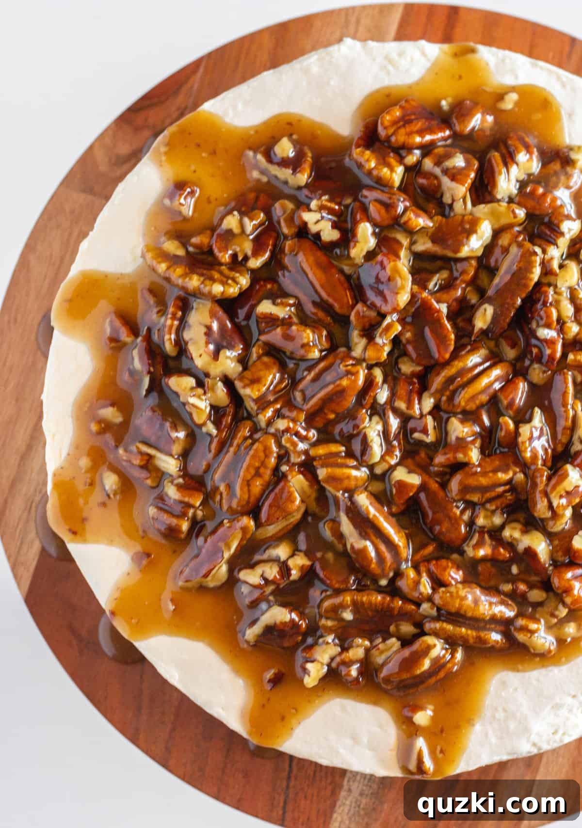 Looking down on top of a whole Pecan Pie No Bake Cheesecake on a wood serving plate.