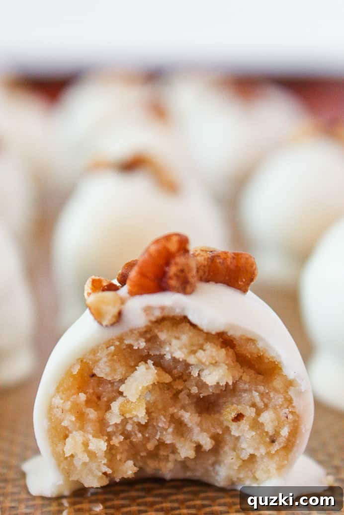 A beautifully arranged tray of pecan sandies truffles, one with a delicate bite taken out, revealing its creamy interior.