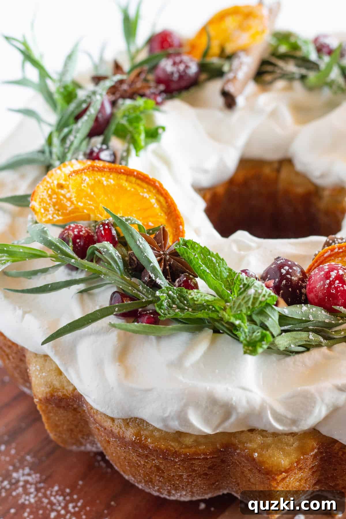 Festive Bundt Wreath Delight 2 A close-up photo of a beautifully decorated Christmas Bundt Cake designed as a wreath, adorned with fresh herbs, cranberries, and orange slices.