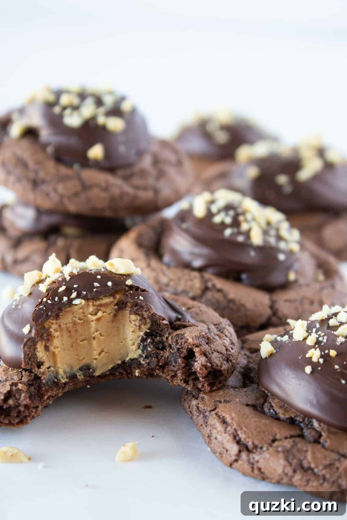 7 Effortless and Amazing Thumbprint Cookies 8 A generously filled plate of Buckeye Brownie Cookies, crafted from a convenient brownie mix, and each adorned with rich chocolate-covered peanut butter truffles and a scattering of chopped peanuts.