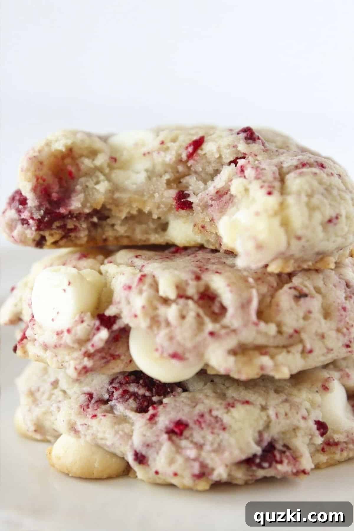 20 Festive Cake Mix Cookies Made Easy 16 A delightful stack of three Subway Copycat Raspberry Cheesecake Cookies, with a tempting bite taken from the top one, revealing its luscious interior.