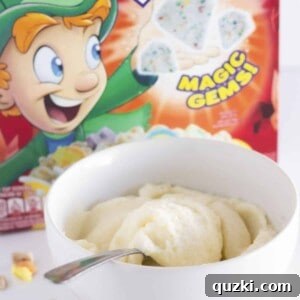 A bowl of cereal milk frosting with Lucky Charms in the background.