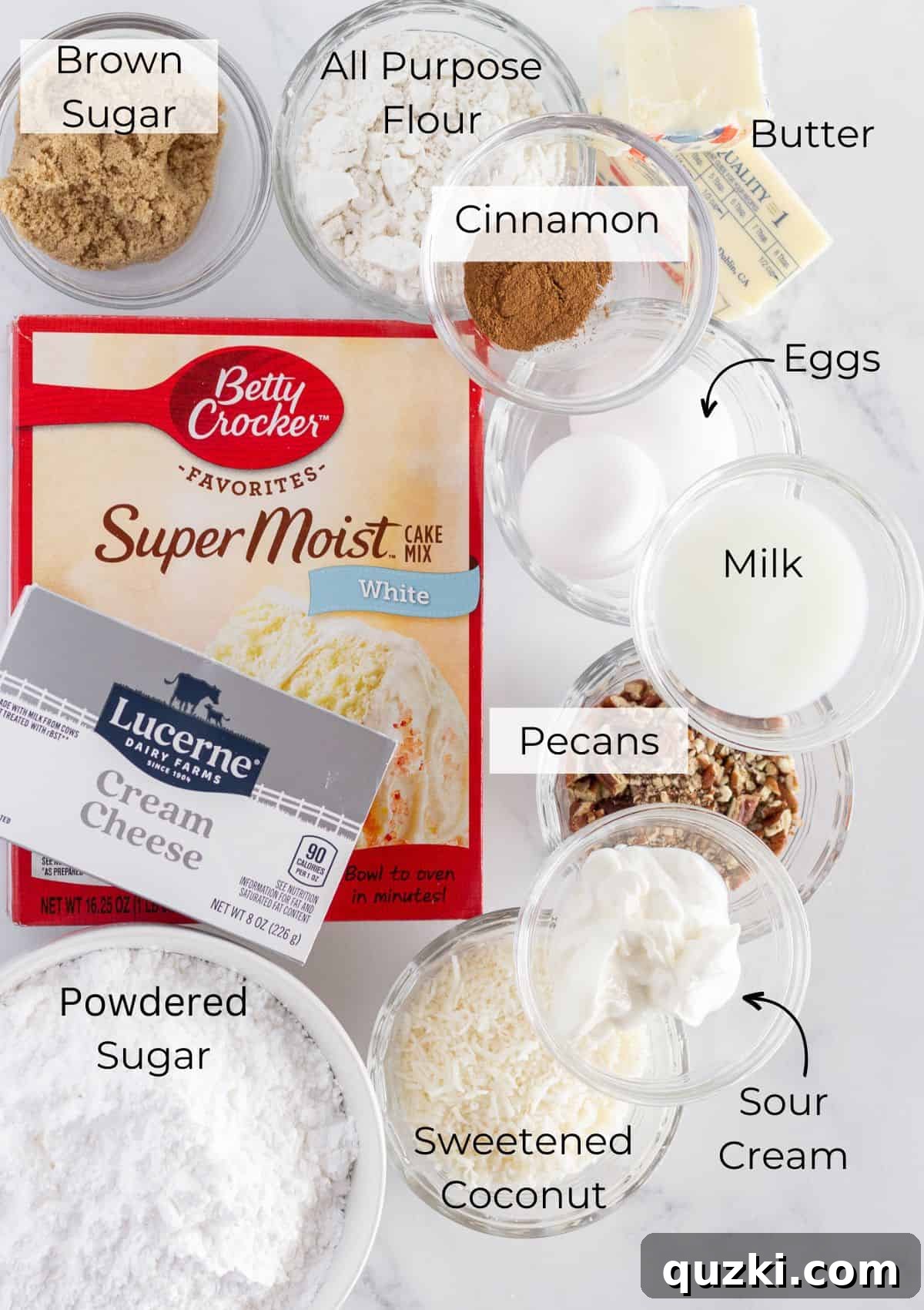 All of the ingredients needed to make coconut pecan cookies with a cake mix, neatly arranged on a counter, ready for baking. Includes a box of cake mix, flour, sugar, eggs, butter, sour cream, coconut, and pecans.