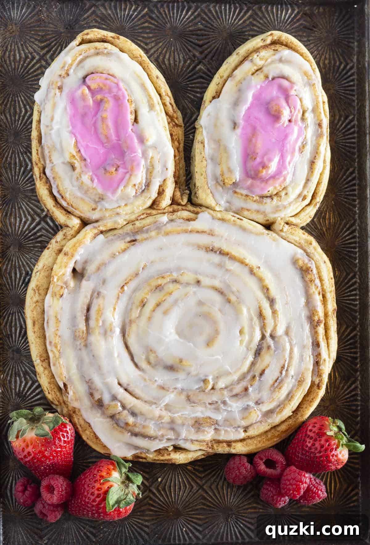 Hoppy Cinnamon Delights 2 A giant bunny cinnamon roll made with refrigerated cinnamon rolls, artfully arranged and served alongside fresh strawberries and raspberries for a vibrant Easter breakfast spread.