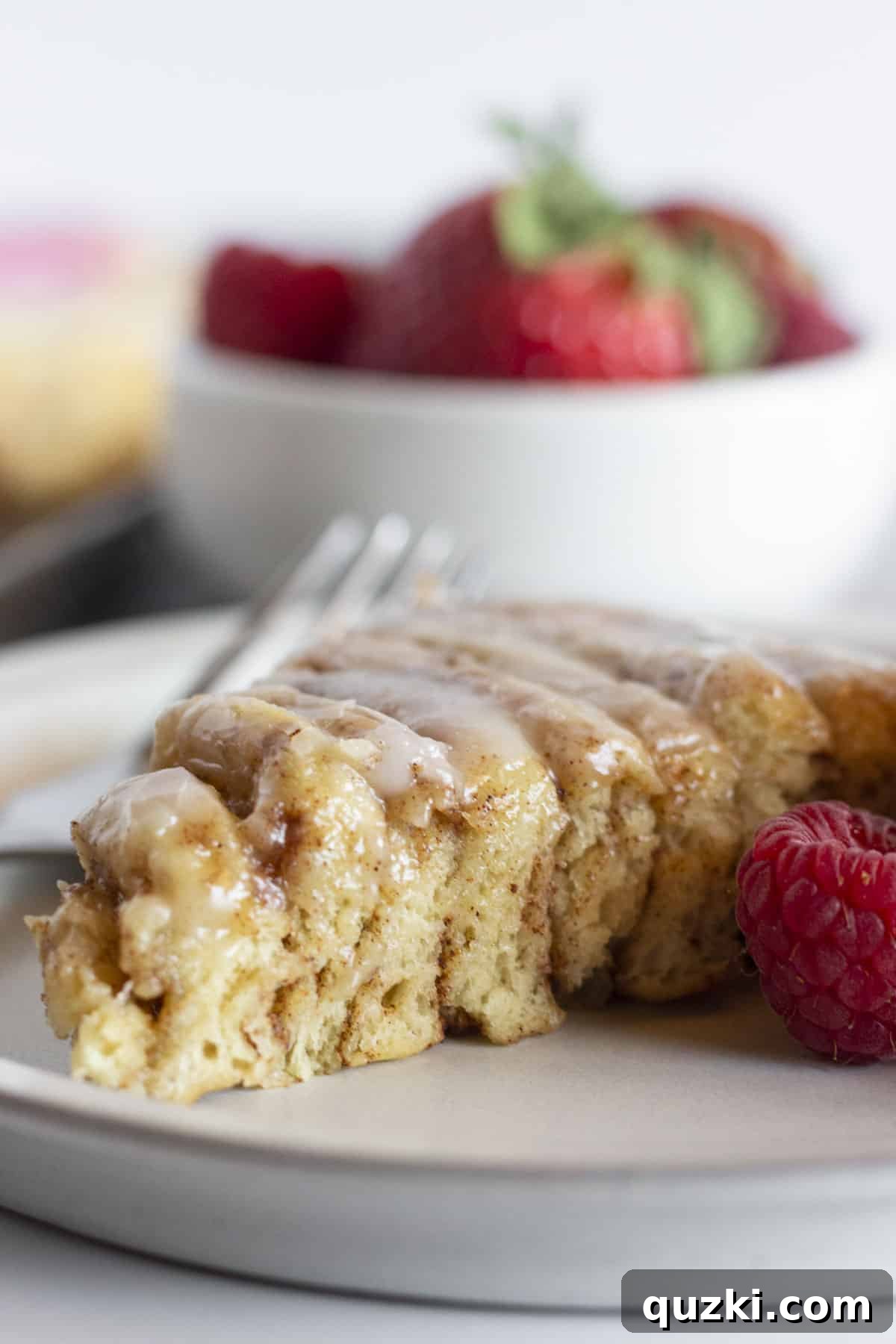 Hoppy Cinnamon Delights 8 A perfectly cut slice of the giant bunny cinnamon roll, showcasing its soft, gooey interior, beautifully frosted and served with a vibrant garnish of fresh strawberries and raspberries, inviting everyone to enjoy.