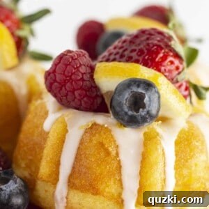 Mini lemon bundt cakes on a red cake plate with fresh fruit.