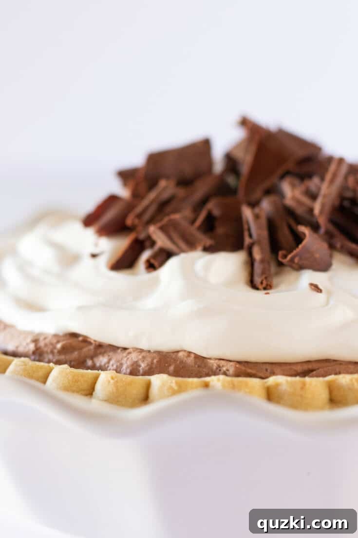 Indulgent chocolate mousse pie with a ready-made crust, made easy with pudding mix, garnished with edible flowers.