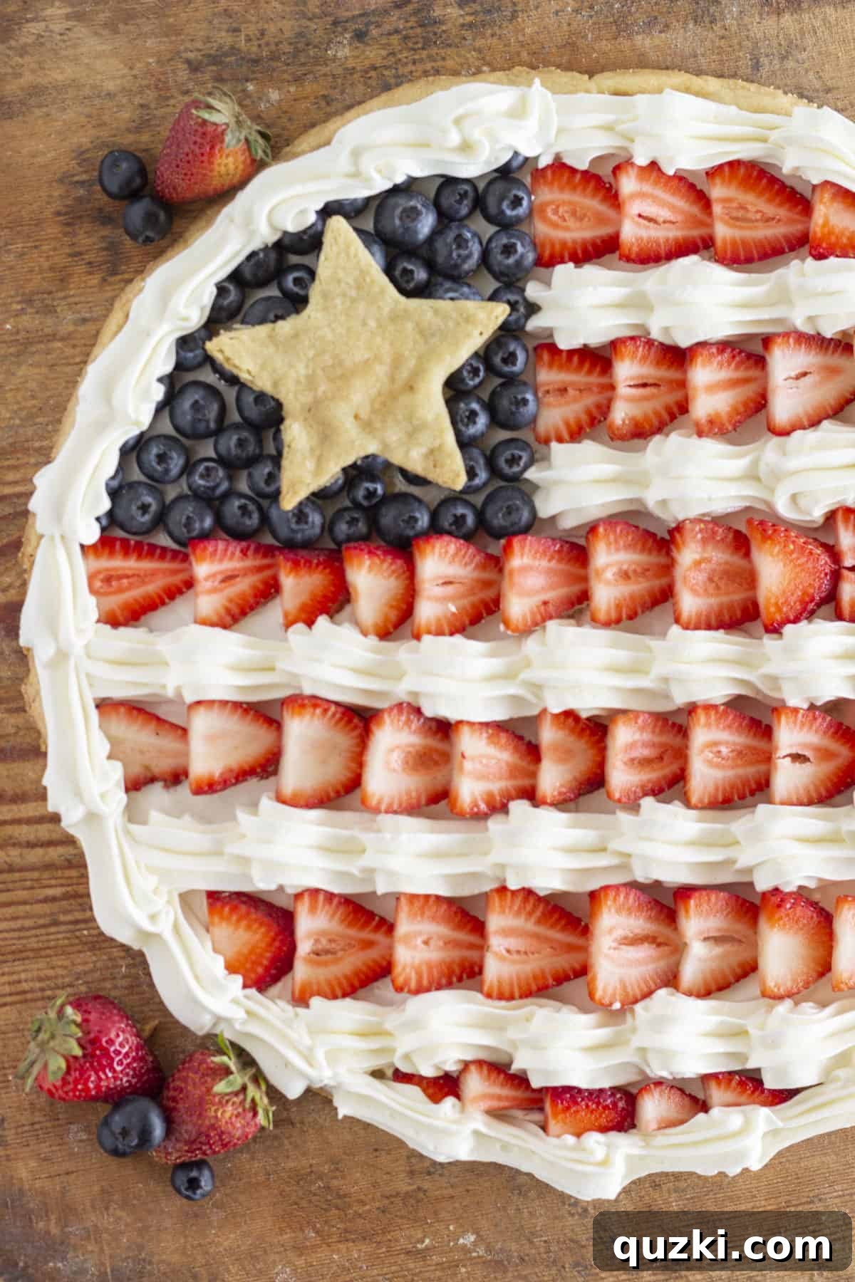 Star-Spangled Fruit Pizza Treat 2 An overhead shot of a whole flag fruit pizza with strawberries and blueberries, perfectly arranged in a flag pattern.