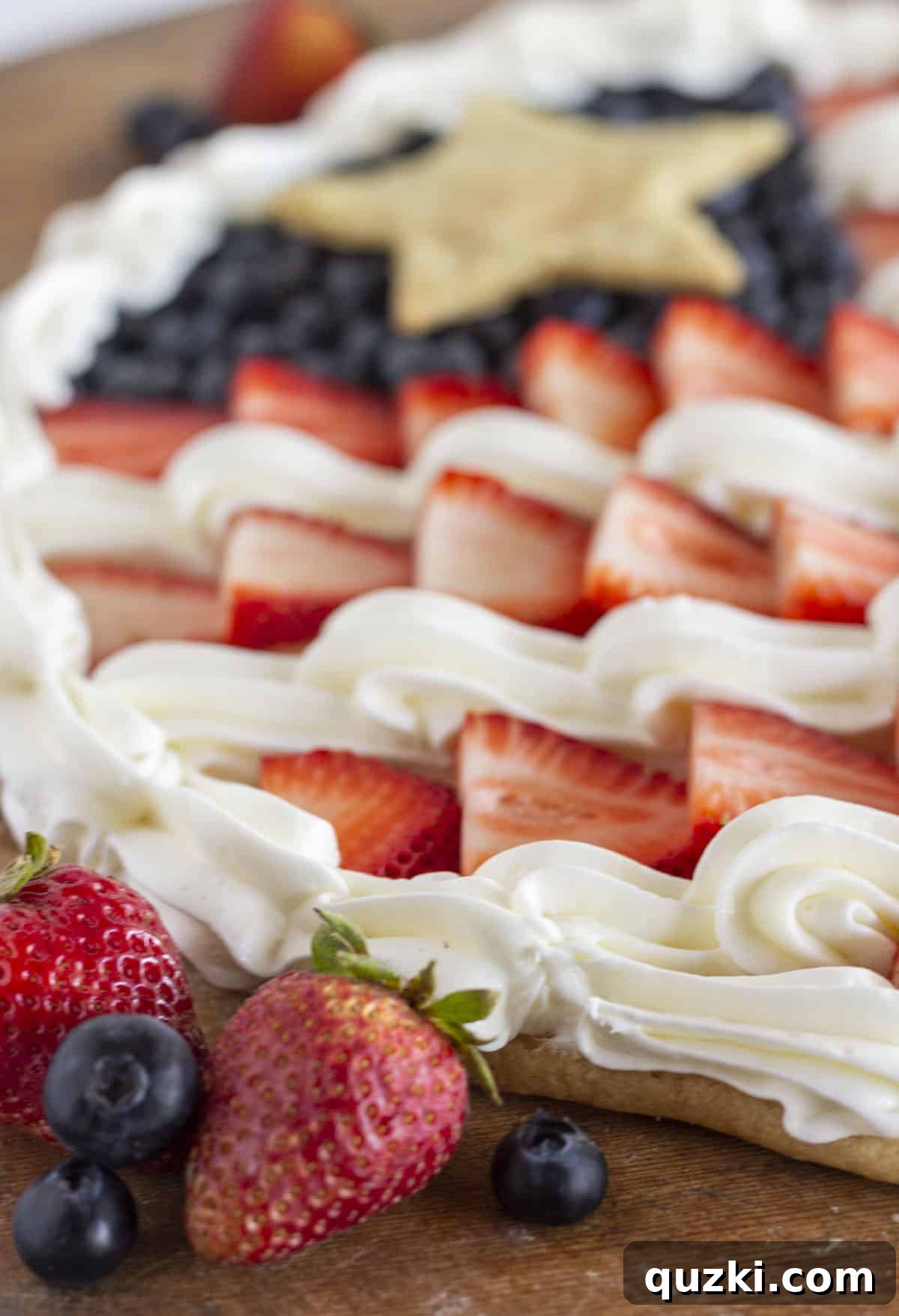 Star-Spangled Fruit Pizza Treat 8 Close-up detailed view of the fresh fruit flag pizza, showcasing the vibrant strawberries and blueberries against the creamy white frosting and golden cookie crust.