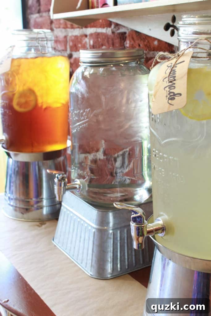 Host a Showstopping Dessert Buffet 12 Rustic drink station with large mason jar dispensers for iced tea, water, and lemonade, encouraging guest self-service.