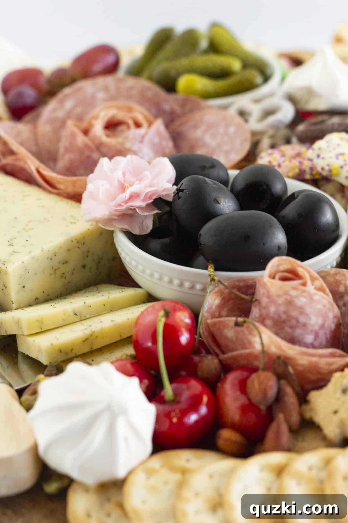 A summer charcuterie board adorned with vibrant fresh flowers and a generous array of fruits, cheeses, and savory bites.