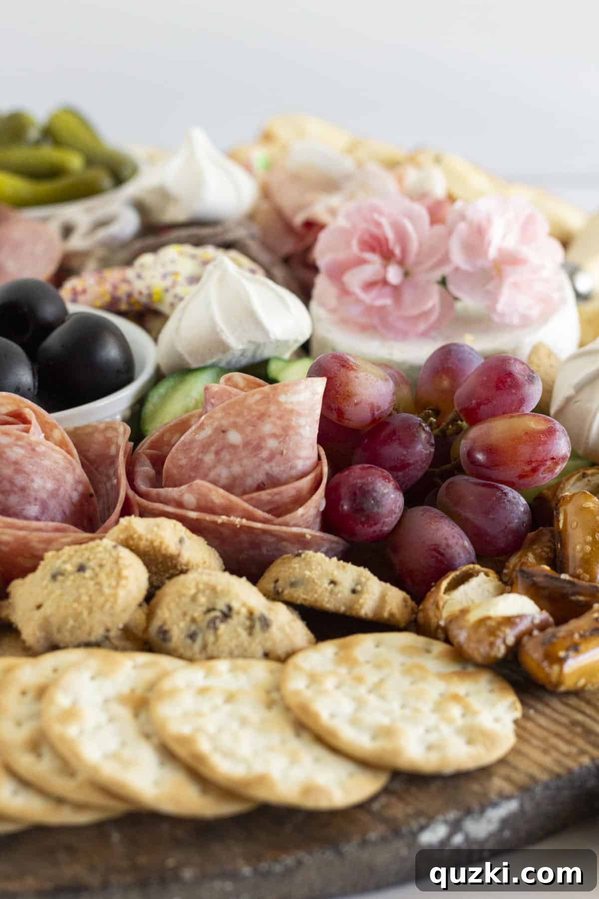 A vibrant summer charcuterie board filled with an assortment of fresh fruit, delicate cookies, and various crackers.