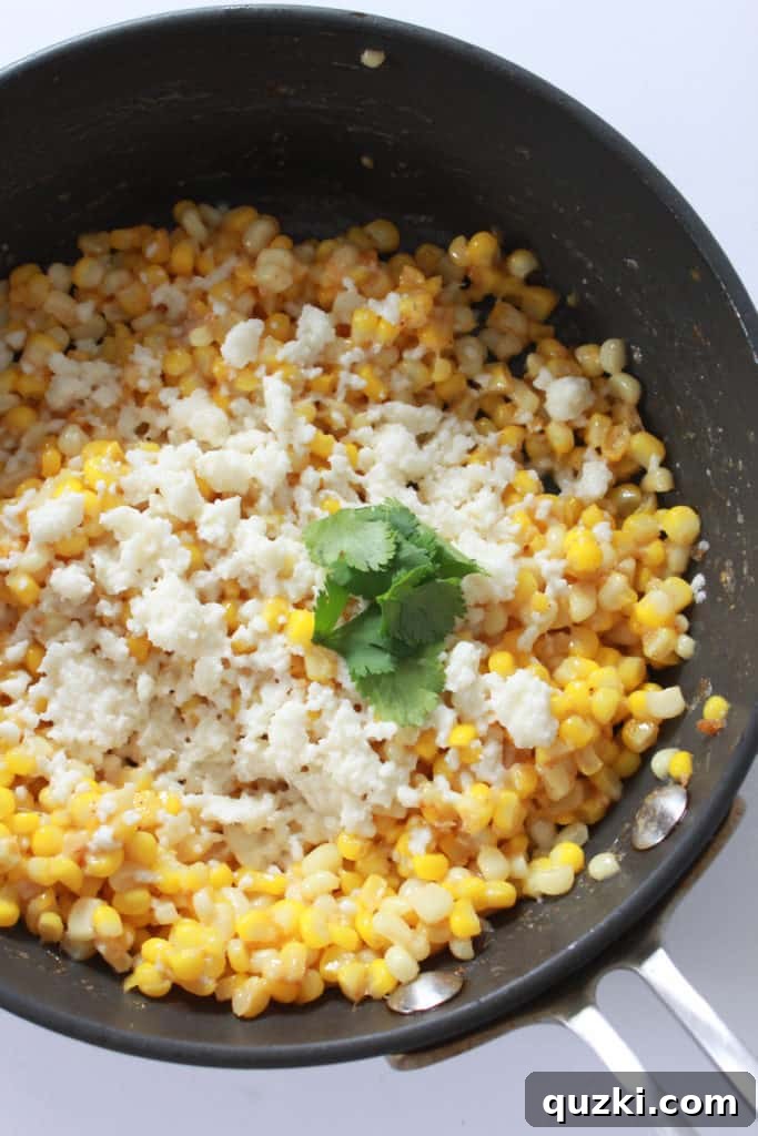Minced garlic mixed with perfectly sautéed corn kernels in a skillet, infusing the dish with aromatic flavor.