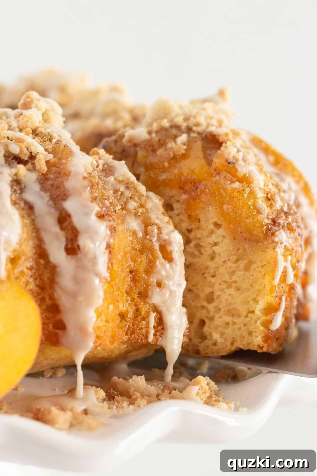 Luscious Peach Cobbler Pound Cake 2 A beautifully baked peach cobbler pound cake, golden brown with a luscious crumb topping and glaze, with a slice being served, revealing the peach filling inside.