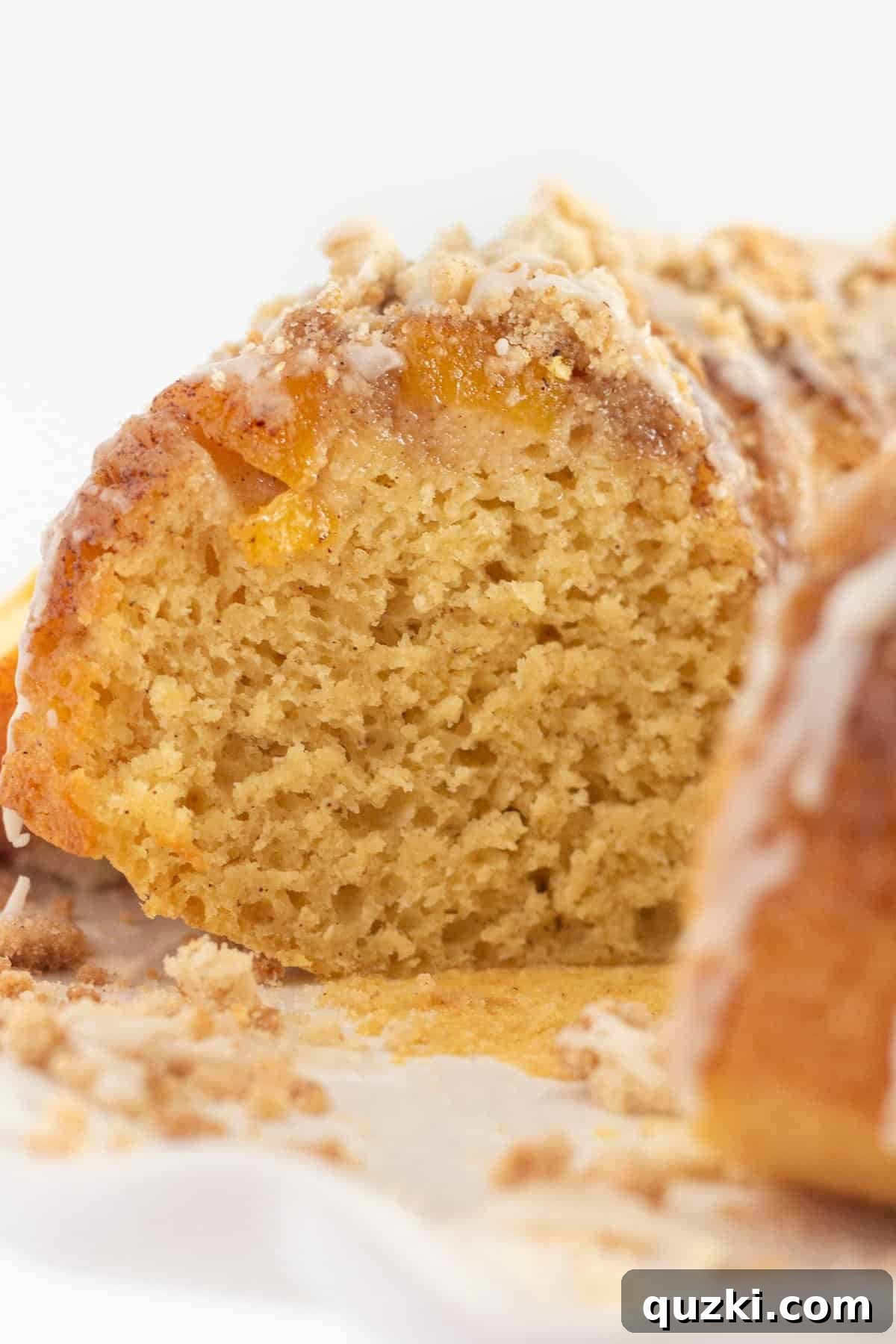 Luscious Peach Cobbler Pound Cake 8 A close-up view of a sliced peach cobbler bundt cake, showcasing the moist interior, visible peach chunks, and generous crumb topping, emphasizing its delicious texture and layers.
