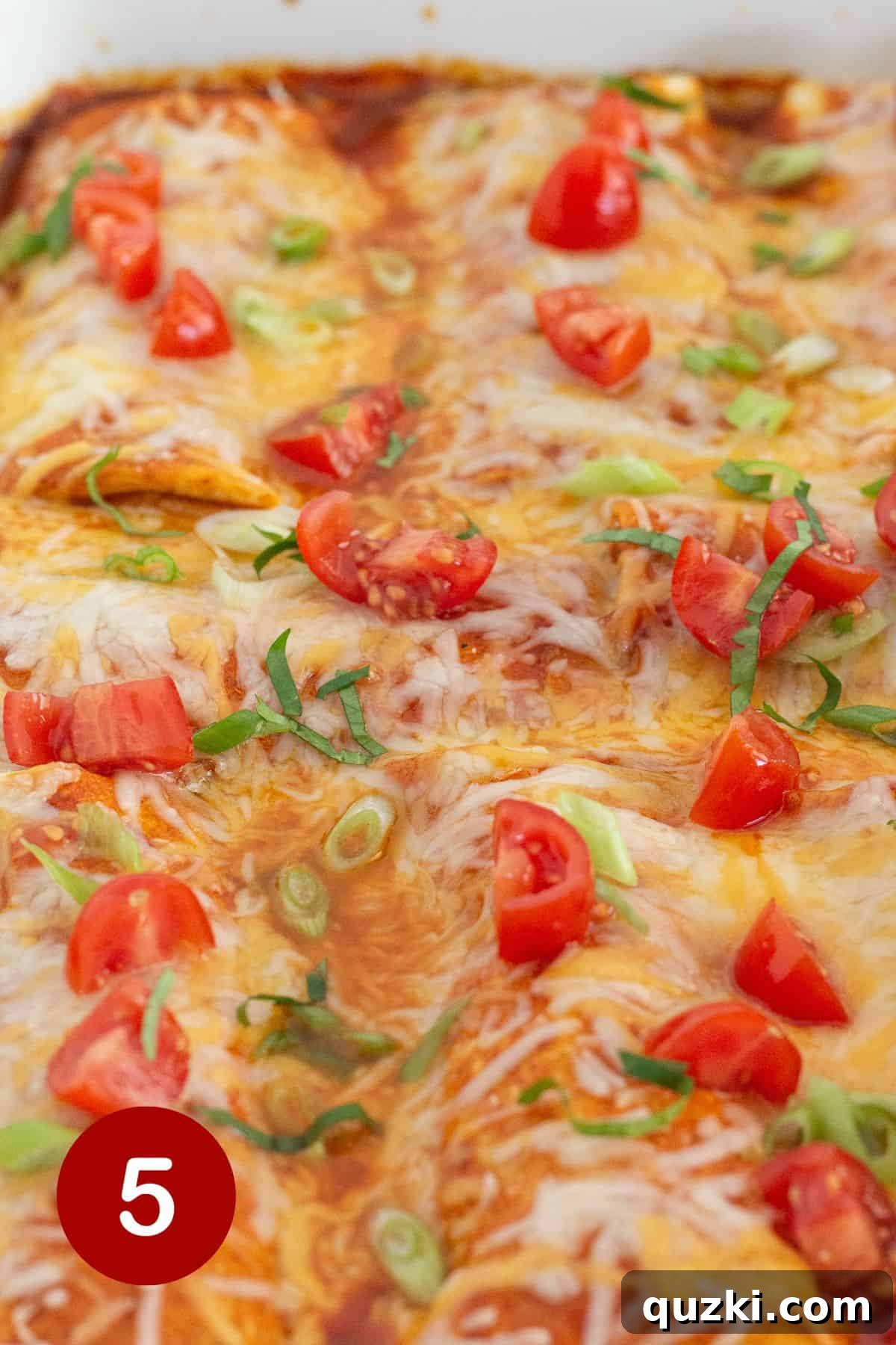 Frozen Burrito Fiesta Bake 6 Close-up shot of the baked frozen burrito casserole, generously topped with chopped fresh tomatoes, bright green onion slices, and a dollop of sour cream.