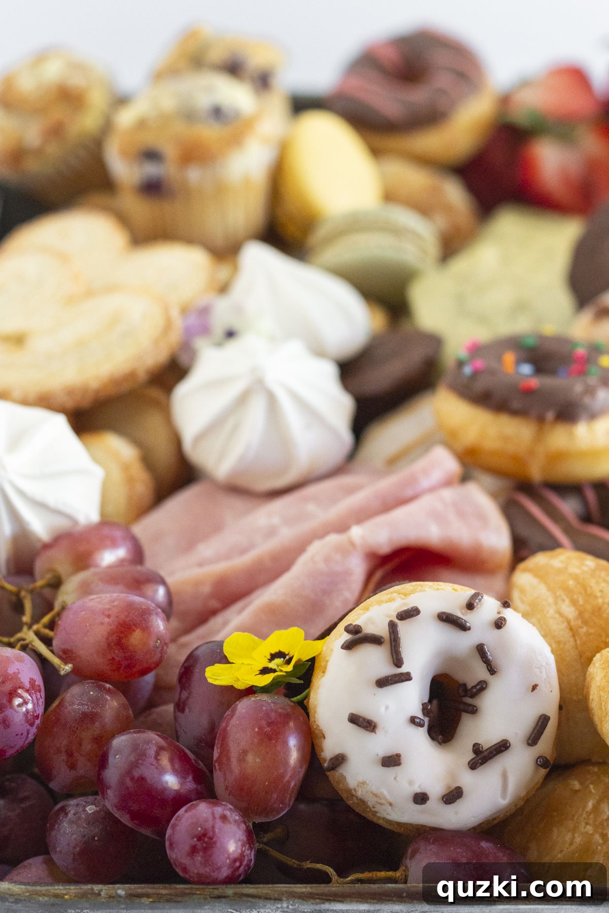 A close-up view of a bountiful breakfast charcuterie board, showcasing mini pastries and fresh berries.
