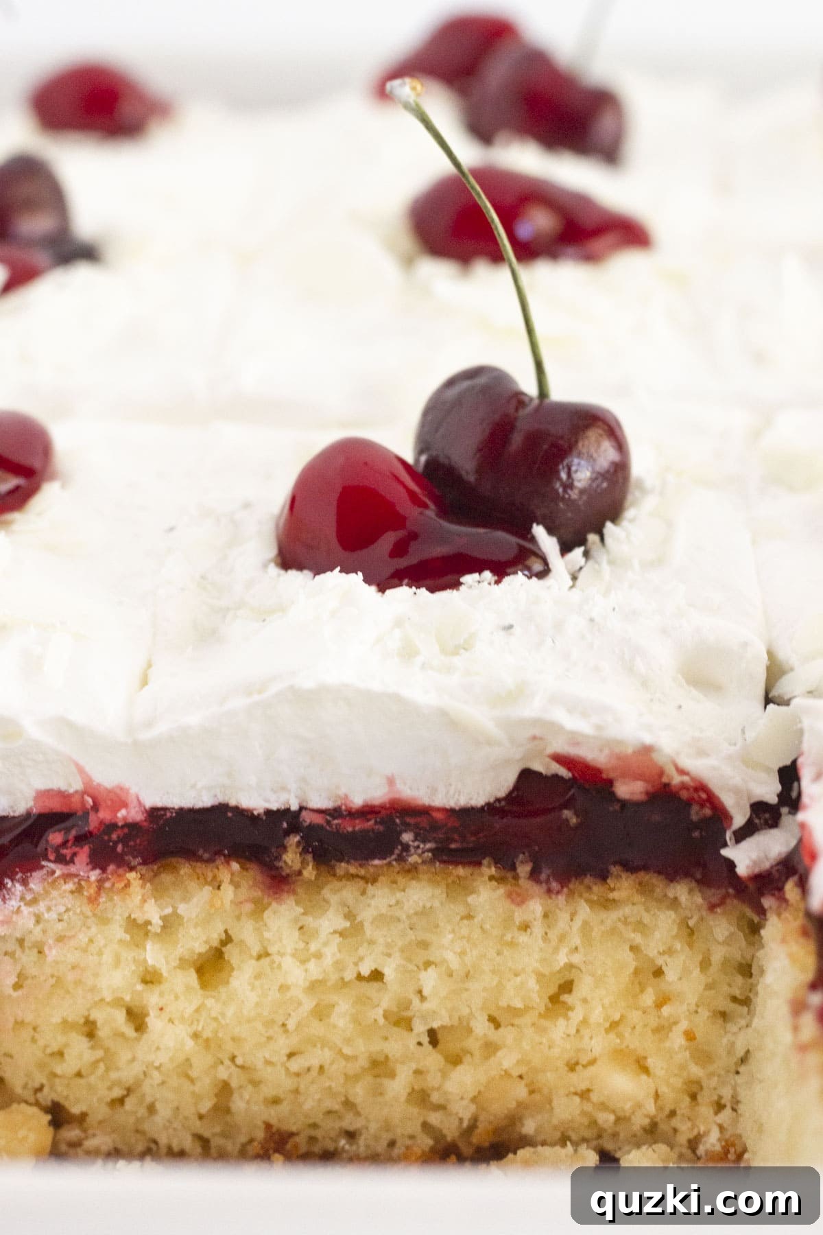 Effortless White Forest Indulgence 7 A close-up view of the interior of a White Forest Cake, revealing its moist white cake layers, abundant cherry filling, and fluffy whipped cream, topped with fresh cherries.