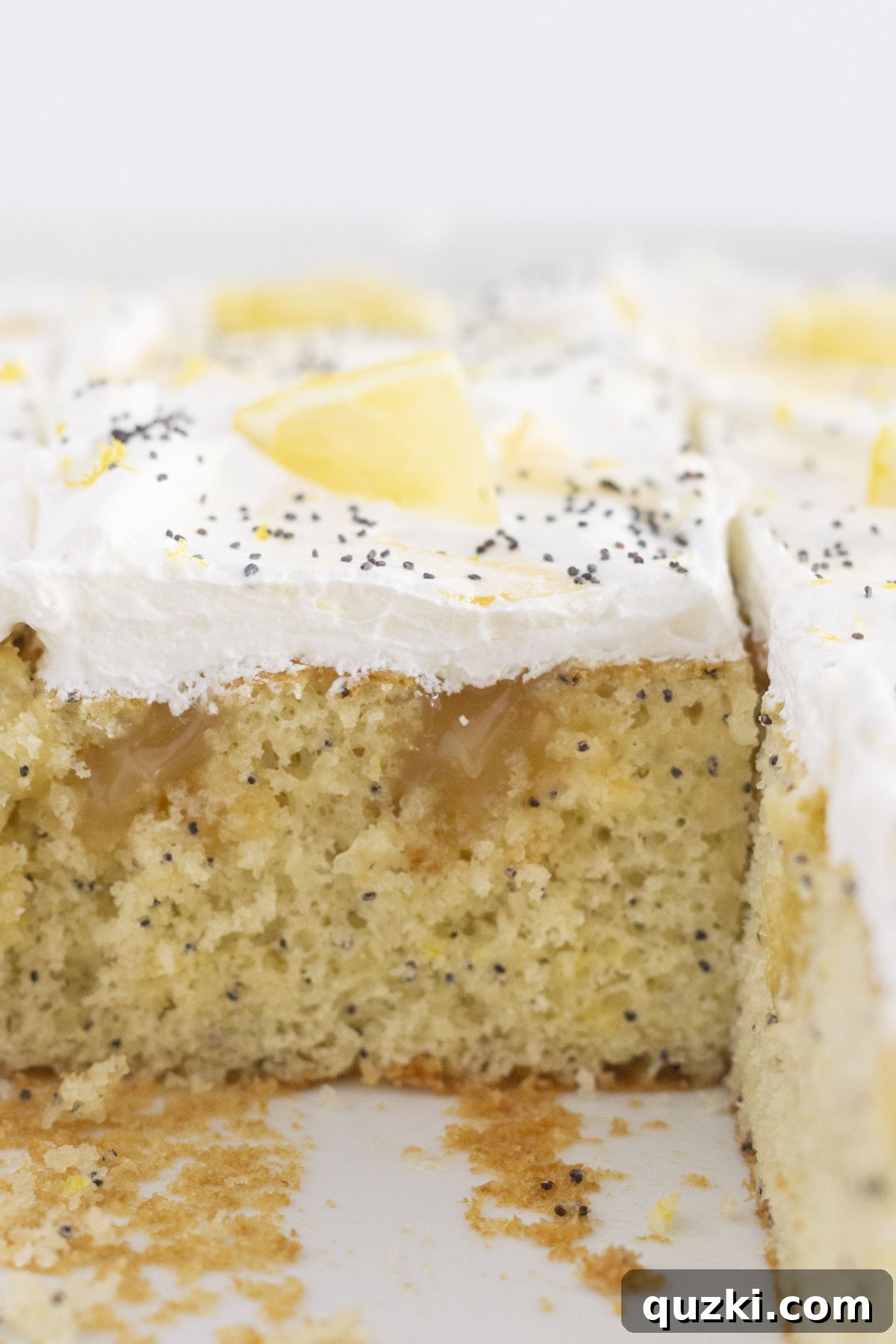 A whole lemon curd cake with a few slices already removed, showcasing its moist interior and generous filling.
