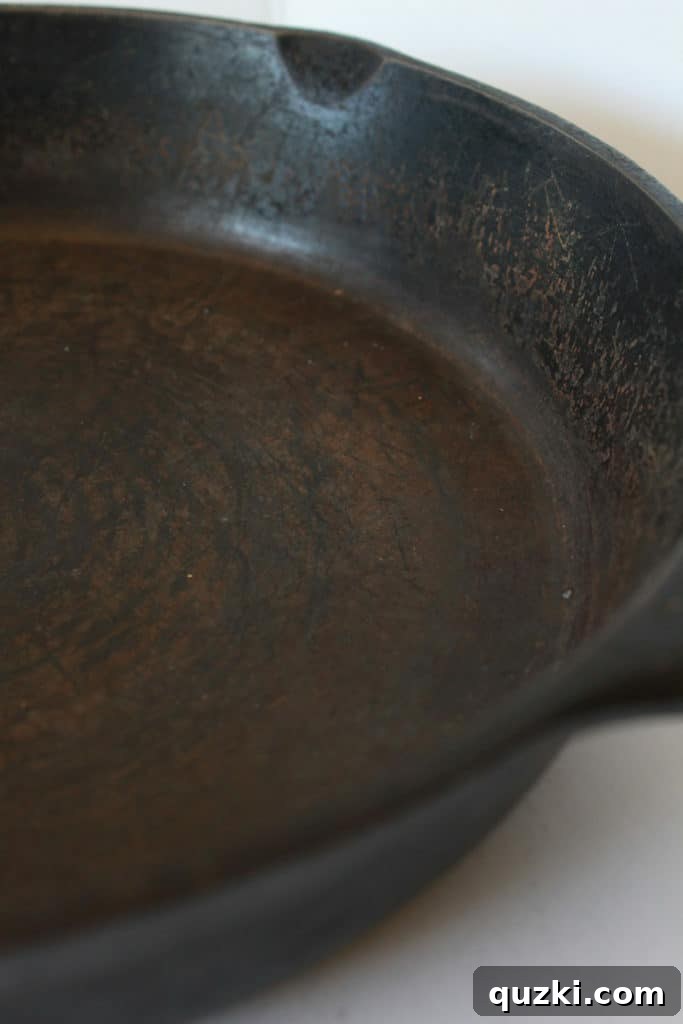 Unlock the Full Potential of Your Cast Iron 3 Close-up of a dry, scratched, and slightly rusty cast iron skillet before seasoning, showing its initial condition.
