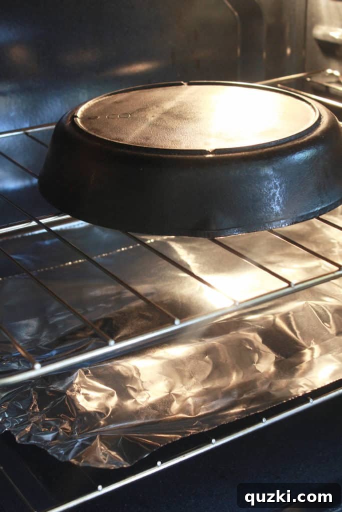 Unlock the Full Potential of Your Cast Iron 6 Cast iron skillet baking upside down in a preheated 375-degree oven, with foil on the bottom rack to catch drips.