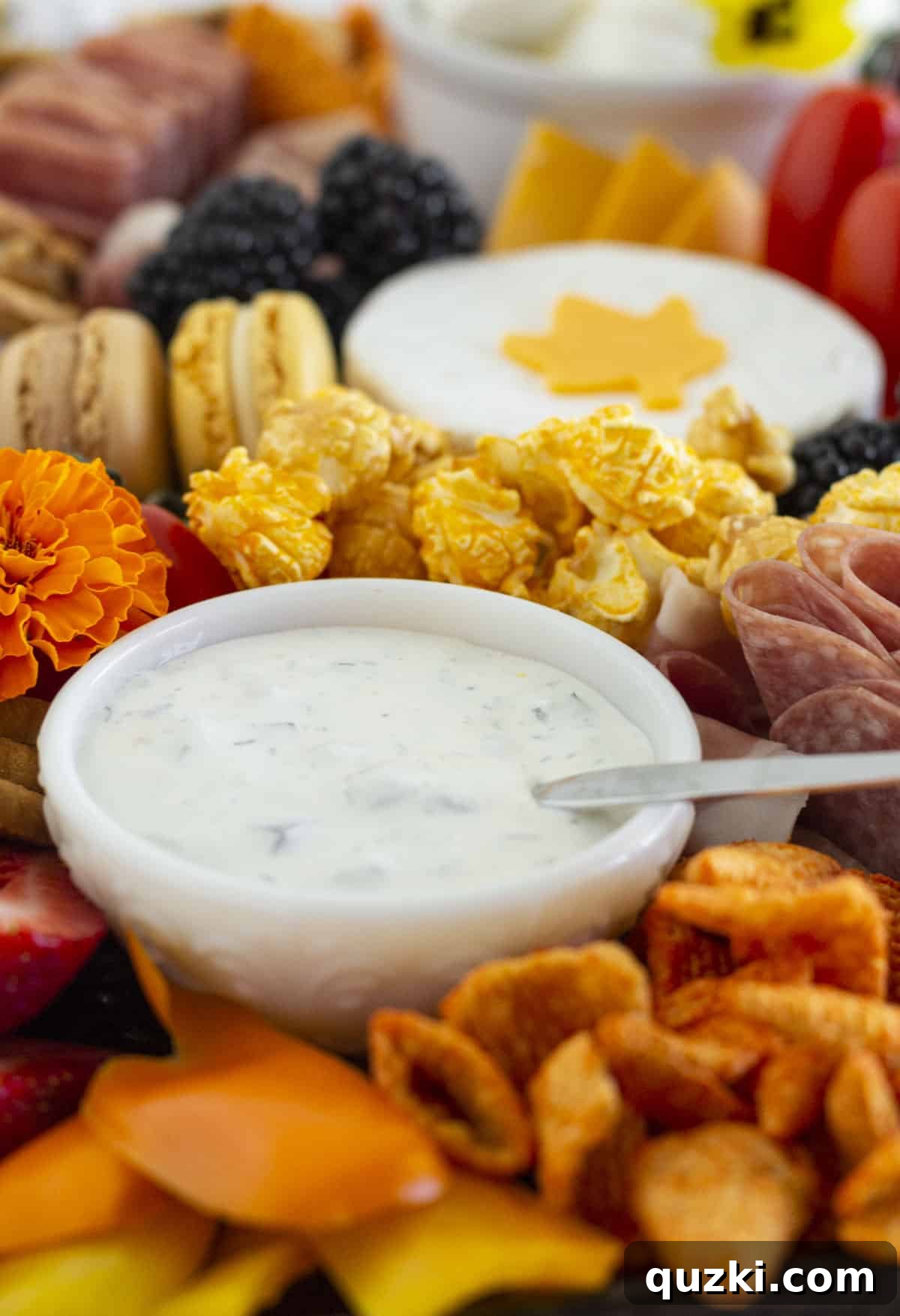 A fall charcuterie board with ranch dip in a small bowl, surrounded by various ingredients.