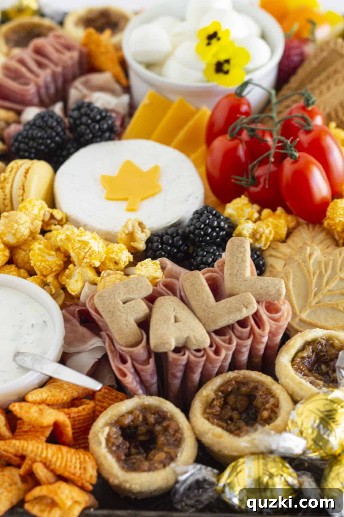 A close up of a Fall Charcuterie Board with cheese in the shape of leaves, and an array of colorful autumn ingredients.
