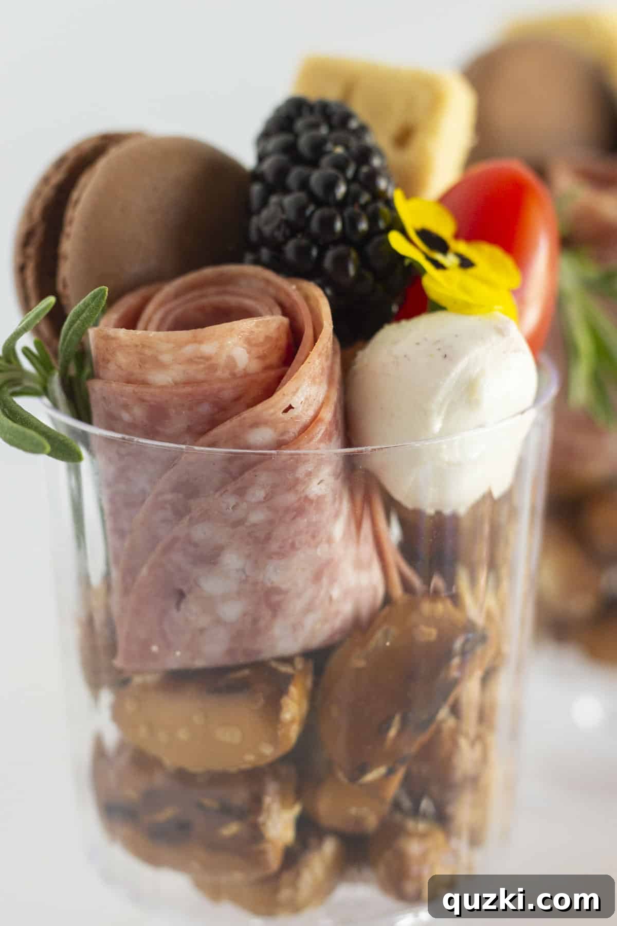 A close-up shot of individually prepared charcuterie cups, showcasing a variety of small food items and garnishes in clear cups.